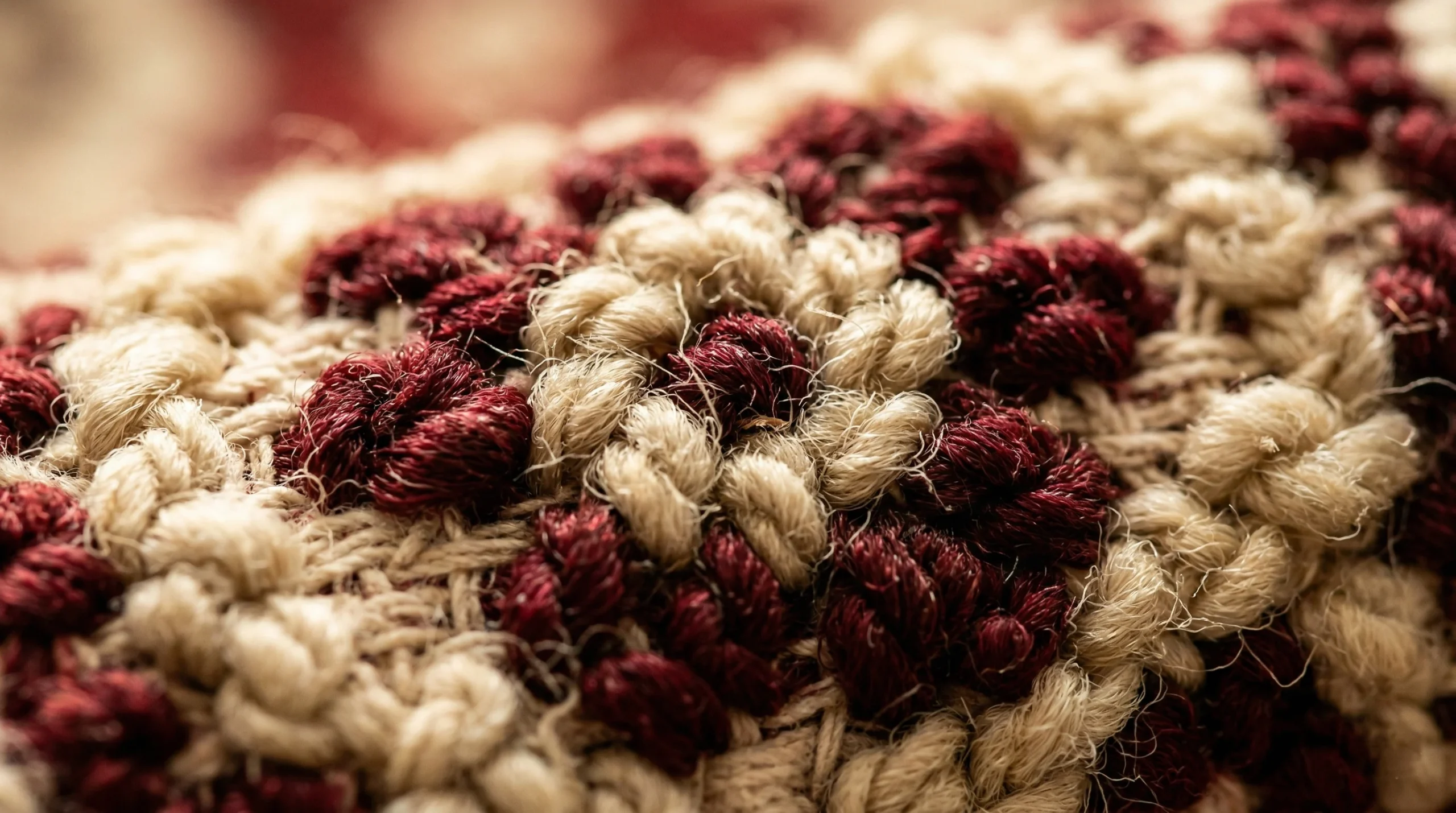 Macro photographie des nœuds de laine naturelle d'un tapis persan fait main — texture fibres ivoire et bordeaux, teintures végétales, 120 000 nœuds au m²